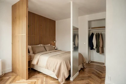 Suite parentale de 15m2 avec cloison basse en bois naturel séparant le coin lit du dressing dans un appartement moderne