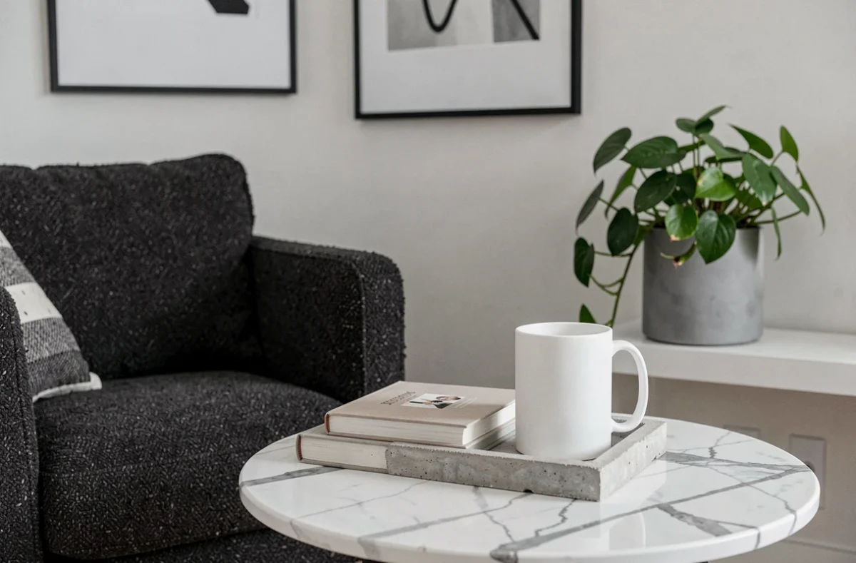 Coin salon décoratif avec fauteuil bouclé gris anthracite, table en marbre blanc et accessoires déco neutres pour intérieur cosy